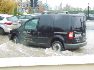 A car driving through the flooded car park.